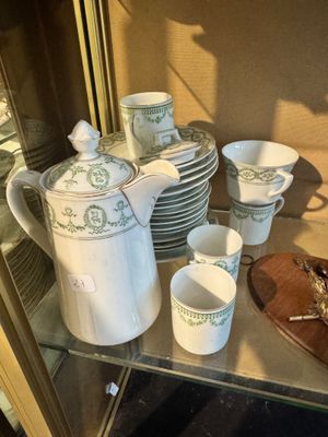 many cups and saucers sitting on a glass shelf