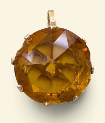 a close up of a yellow diamond pendant on a white background