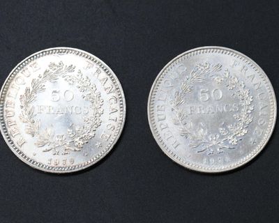 two silver coins sitting side by side on a black surface