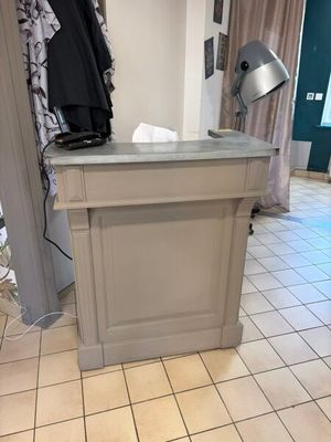 a small counter in the middle of a room with a lamp on it