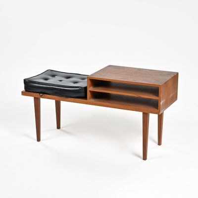 un petit banc en bois sur lequel est posé un pouf noir