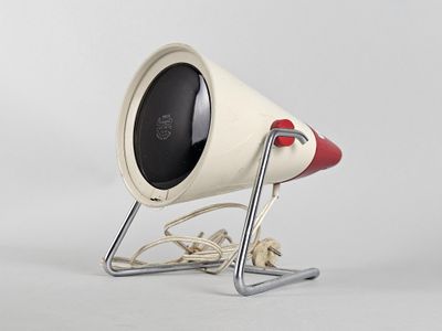 a white and red speaker sitting on a metal stand