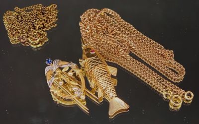 un collier, un bracelet et une bague en or posés sur un fond noir