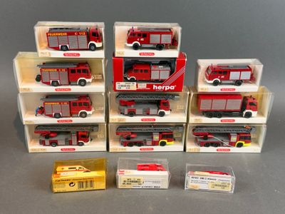 six camions de pompiers rouges et blancs sont rangés dans des boîtes posées sur une surface grise