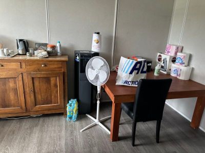 une petite table avec un ventilateur dans un coin de la pièce