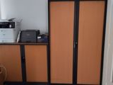 a room with a desk, cabinets, and a printer