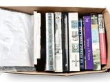 many books in a cardboard box on a white surface