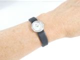 wrist of a woman with a watch on her wrist on a white surface