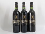 trois bouteilles de vin posées les unes à côté des autres sur une surface blanche