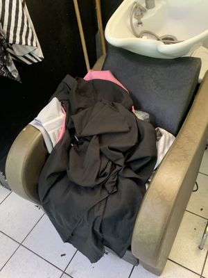 une chaise sur laquelle est posée une pile de vêtements, à côté d'un lavabo