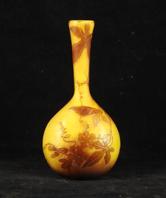 yellow and brown vase with flowers on it against a black background