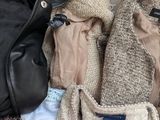 a pile of clothes and a jacket sitting on a bed