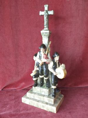 figurine représentant un groupe de personnes assises au sommet d'une croix