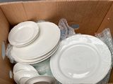 a cardboard box filled with white plates and bowls