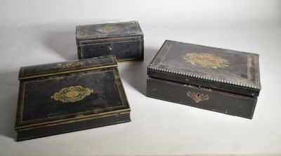 Trois boîtes noires sont posées sur une table devant un fond blanc.