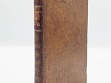 an old book sitting on top of a white table next to a white wall