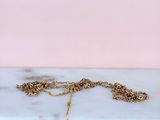 a close up of a gold necklace on a marble surface
