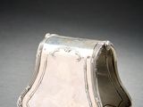 un porte-monnaie ancien en argent posé sur une surface grise avec un fond noir
