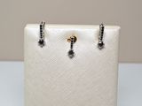 a pair of black and white diamond earrings sitting on top of a white purse