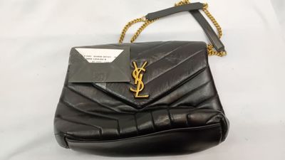 un sac à main noir muni d'une bandoulière en chaîne dorée et d'une étiquette