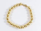 a close up of a gold beaded bracelet on a white background