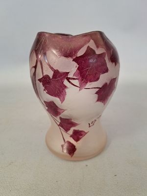 purple and white vase with red leaves on it sitting on a white surface