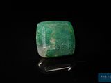 a close up of a green stone on a black surface