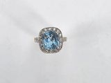 a close up of a ring with a blue topaz stone surrounded by diamonds