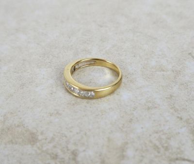 un gros plan d'une bague en or sertie de diamants posée sur une surface en marbre