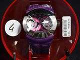 une montre violette dans un écrin rouge posée sur une surface noire