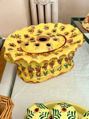 une assiette jaune ornée d'un motif floral, à côté d'un panier rempli de fleurs