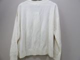 the white sweater is hanging on a hanger on the wall