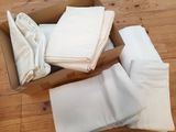 une boîte remplie de draps blancs pliés, posée sur un plancher en bois