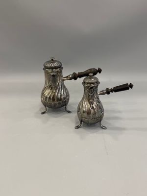 a pair of silver salt and pepper shakers on a white surface