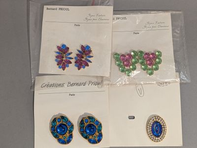 Trois paires de boucles d'oreilles et des broches sont exposées sur une table