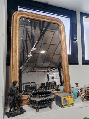 un miroir posé sur une étagère dans une pièce, près d'une fenêtre