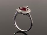 a close up of a ring with a red stone surrounded by white diamonds
