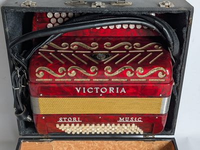 a red accordion sitting in a case on a table