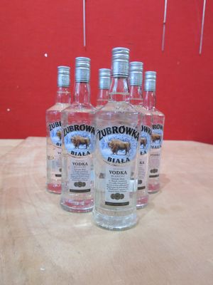 quatre bouteilles de vodka posées sur une table devant un mur rouge