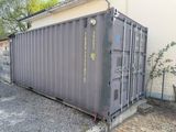 un grand conteneur gris posé contre le mur d'un immeuble