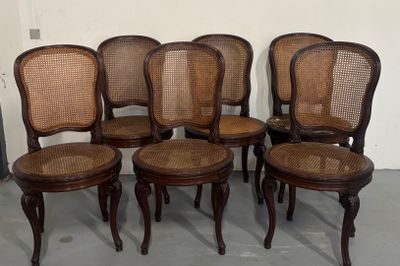 six chaises à assise en osier sont alignées en rangée