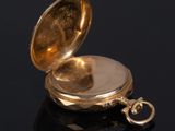a close up of a gold pocket watch on a black surface