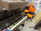 a piano and a chair in a room with a lot of clutter