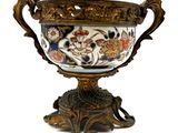 un grand vase décoré, posé sur un socle, sur fond blanc