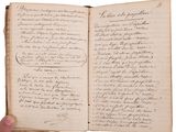 an old book with writing on it and a hand holding a pen