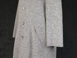 a grey coat on a mannequin stand against a black background