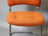 an orange chair sitting next to a white wall on a gray floor
