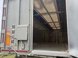 à l'arrière d'un camion dont la porte est ouverte, sur un chemin de terre
