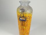 yellow and blue vase sitting on a white surface with a white background