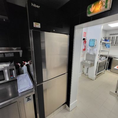 réfrigérateur en acier inoxydable dans une cuisine professionnelle équipée de plans de travail en acier inoxydable